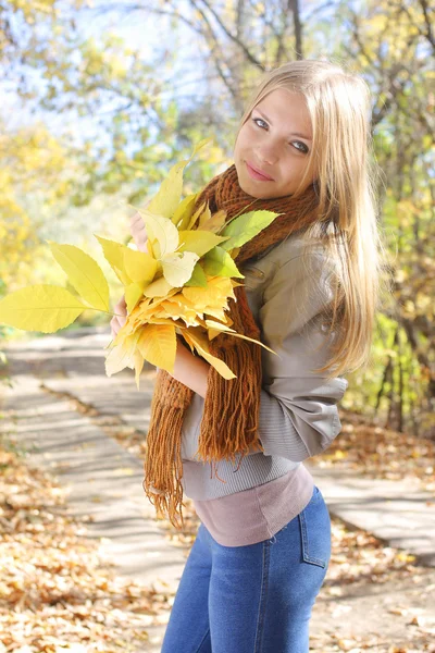 Fille tenant un tas de feuilles dans le parc — Photo