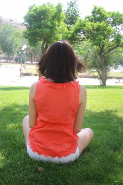 genç esmer kadın oturup geri yeşil çimen