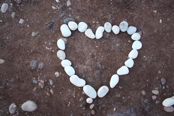 Taş kum zemin üzerine beyaz kalp — Stok fotoğraf
