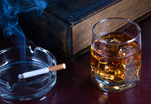 Виски, сигарета и старая книга поблизости — стоковое фото