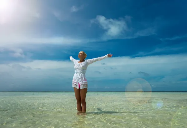 Woman with wide open arms standing by the tropical sea — Stock Photo, Image
