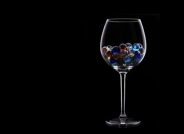 Small colored balls inside glass on the black background — Stock Photo, Image