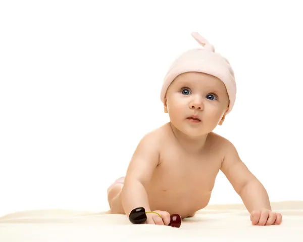 Lilla bebis tittar in i kameran och bär en hatt på den vita bakgrunden — Stockfoto