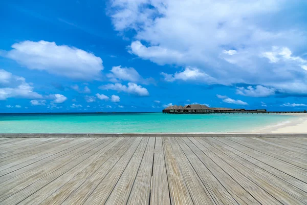 Muelle gris de madera en la playa perfecta en un día soleado con cielo azul — Foto de Stock