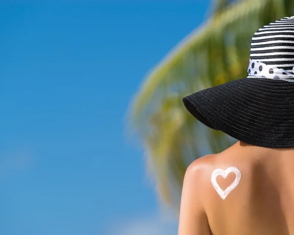 Vrouw met hart gevormde zonnebrandcrème — Stockfoto