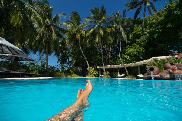 女性的脚热带池上蓝色的海水中的特写镜头。假期假期. — 图库照片