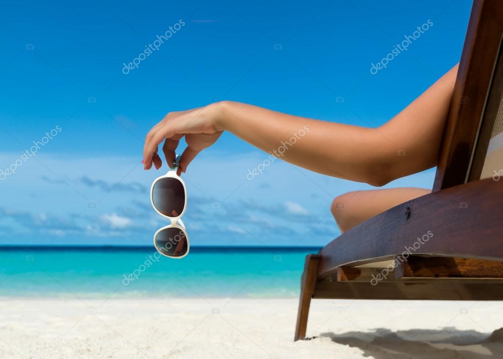 Young girl lying on a beach lounger with glasses in hand on the tropical island