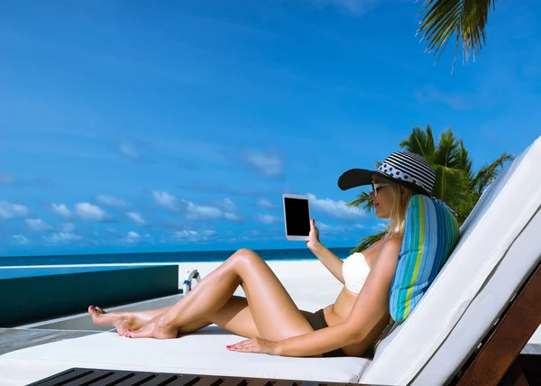 年轻女子在 tablet pc，在海滩的帽子 — 图库照片
