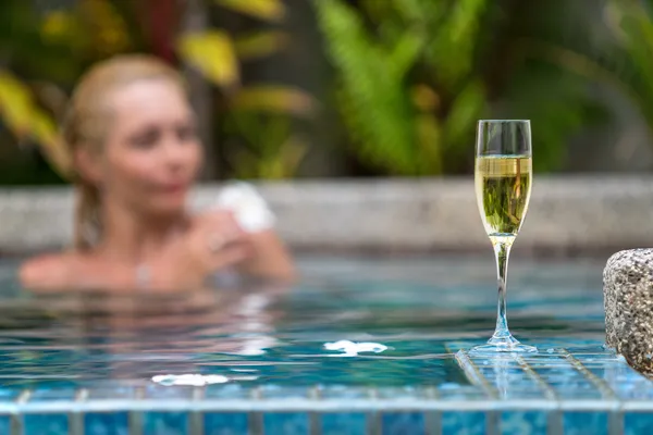 Champagne nära pool på en bakgrund av en vacker kvinna koppla av — Stockfoto