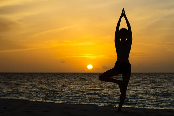 Donna di yoga seduta sulla costa del mare al tramonto . — Foto Stock