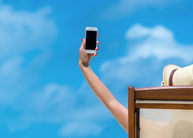 tropik adada elinde cep telefonu ile bir plaj tembel yatan genç kız