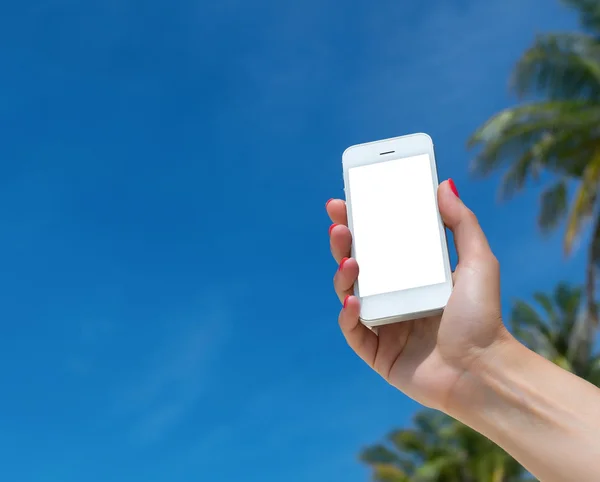Ženská ruka ukazuje prázdnou chytrý telefon na pláži s mořem v pozadí — Stock fotografie