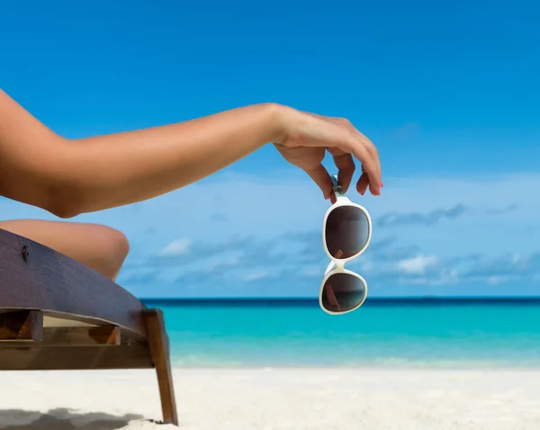 Jong meisje liggen op een ligstoel strand met bril in de hand op het tropische eiland — Stockfoto