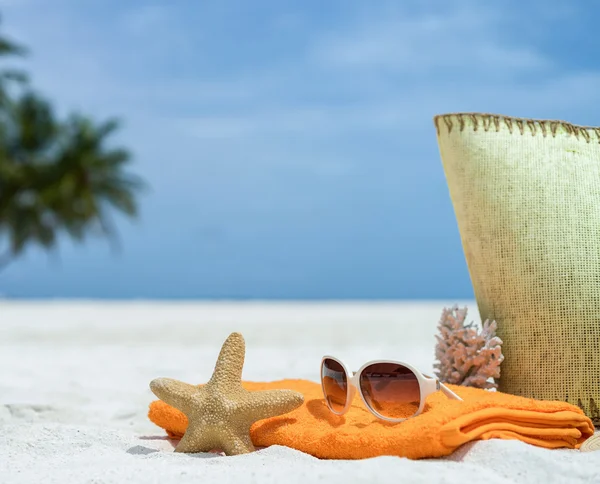Summer beach bag with starfish,towel,sunglasses and flip flops on sandy beach — Stock Photo, Image