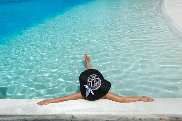 Vrouw met hoed ontspannend bij het zwembad — Stockfoto