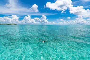 Egzotik adanın önündeki berrak tropik sularda şnorkelle yüzen adam