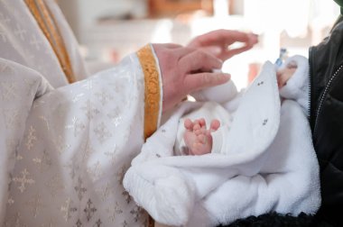 Vaftiz töreni. Rahip, çocuğu vaftiz töreniyle vaftiz ediyor.