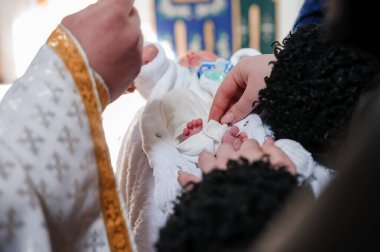 Vaftiz töreni. Rahip, çocuğu vaftiz töreniyle vaftiz ediyor.