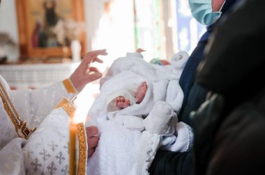 Vaftiz töreni. Rahip, çocuğu vaftiz töreniyle vaftiz ediyor.