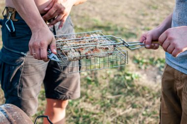 Erkekler yaz aylarında et şişlerini ızgaraya koyarlar.