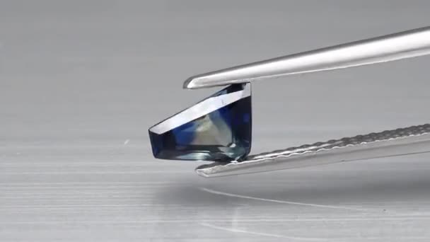 Natural blue sapphire gemstone in the tweezers — Stock Video