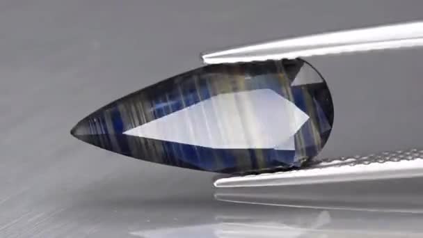 Natural blue sapphire gemstone in the tweezers — Stock Video