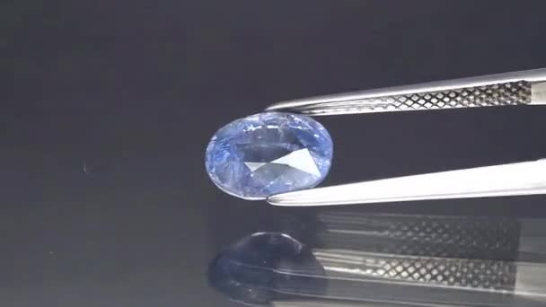 Natural blue sapphire gemstone in the tweezers — Stock Video