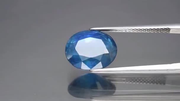 Natural blue sapphire gemstone in the tweezers — Stock Video