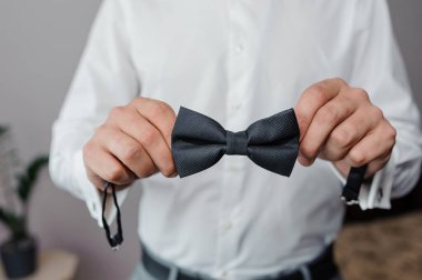 Damadın elinde siyah papyon var. Bir adamın elinde papyon