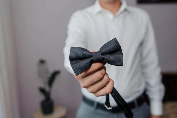 Black bow tie in the hands of the groom. Bow tie in the hands of a man