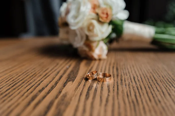 Свадебный букет свежих цветов, пара золотых колец крупным планом. Свадебные детали — стоковое фото