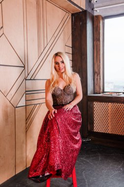 Güzel kırmızı elbiseli bir kız sandalyede oturuyor.