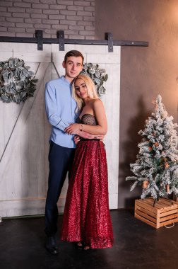 Güzel elbiseli bir kız bir erkeği kucaklıyor ve öpüyor. Yeni yıl fotoğraf oturumu