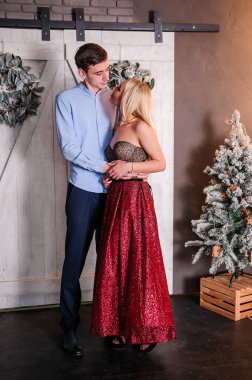 Güzel elbiseli bir kız bir erkeği kucaklıyor ve öpüyor. Yeni yıl fotoğraf oturumu