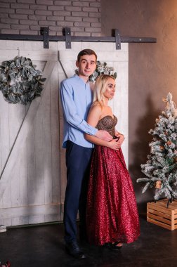 Güzel elbiseli bir kız bir erkeği kucaklıyor ve öpüyor. Yeni yıl fotoğraf oturumu