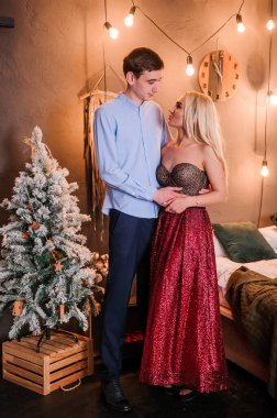 Güzel elbiseli bir kız bir erkeği kucaklıyor ve öpüyor. Yeni yıl fotoğraf oturumu