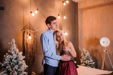 Güzel elbiseli bir kız bir erkeği kucaklıyor ve öpüyor. Yeni yıl fotoğraf oturumu