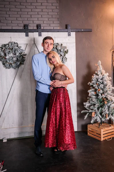 A girl in a beautiful dress hugs and kisses a guy. New Years photo session — стоковое фото