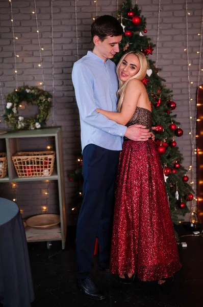 Güzel elbiseli bir kız bir erkeği kucaklıyor ve öpüyor. Yeni yıl fotoğraf oturumu — Stok fotoğraf