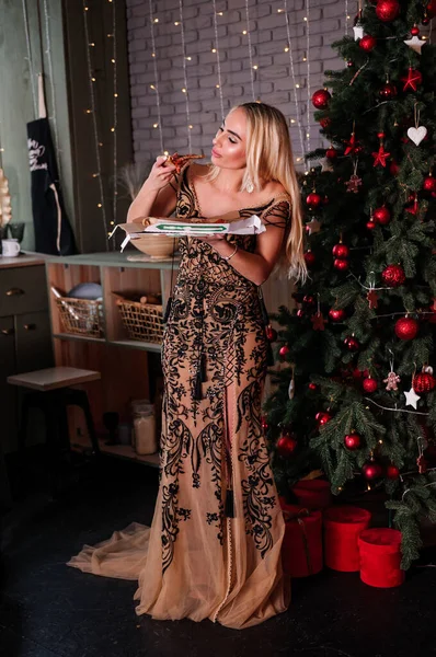 Noel ağacının arka planında duran çok güzel elbiseli kız.