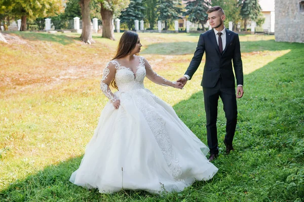 Recém-casados caminham no parque abraçando e beijando — Fotografia de Stock