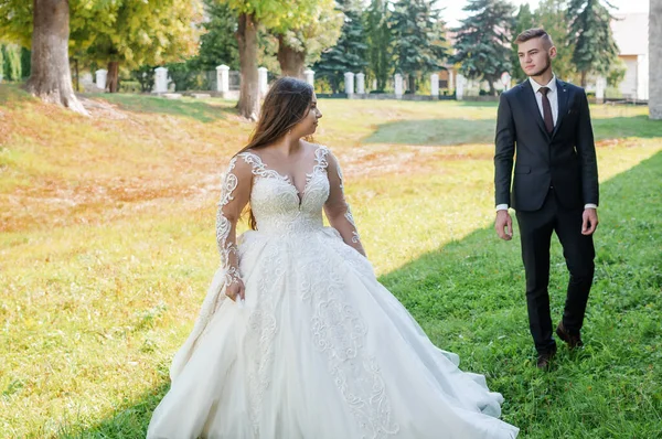 Recém-casados caminham no parque abraçando e beijando — Fotografia de Stock