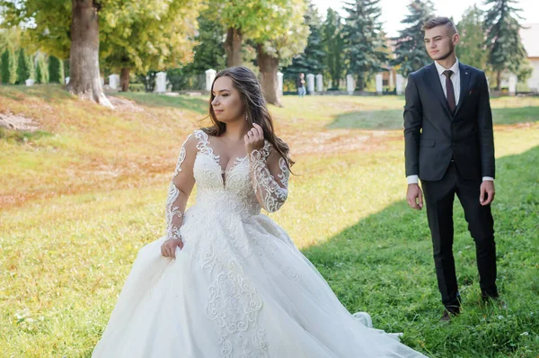 Newlyweds walk in the park hugging and kissing — стоковое фото