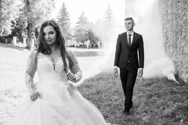 Recém-casados caminham no parque abraçando e beijando — Fotografia de Stock