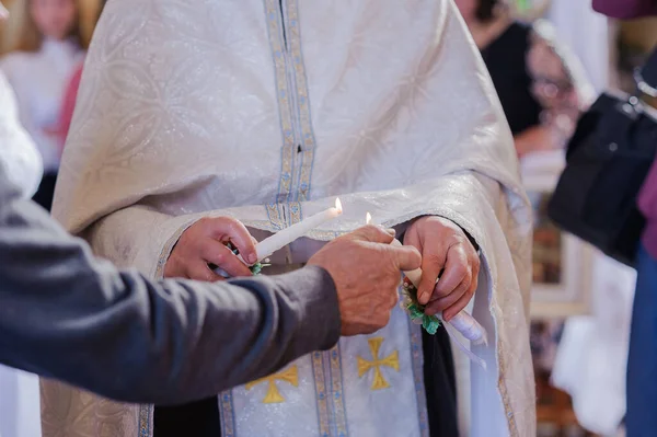 Les mariés tiennent des bougies brillantes pendant la cérémonie dans l'église. Mains de jeunes mariés avec des bougies dans l'église. Détails religieux de l'église. Traditions — Photo