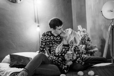 Kazaklı ve kot pantolonlu bir kız yatakta uzanıp sarılıyor.