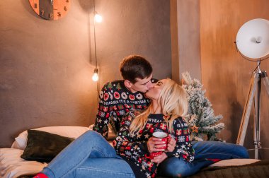 Kazaklı ve kot pantolonlu bir kız yatakta uzanıp sarılıyor.