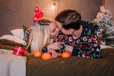 Kazaklı ve kot pantolonlu bir kız yatakta uzanıp sarılıyor.