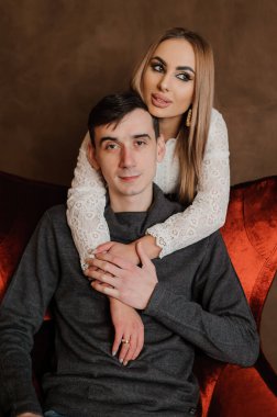 Kız, kırmızı sandalyede oturan bir adama sarılıyor.