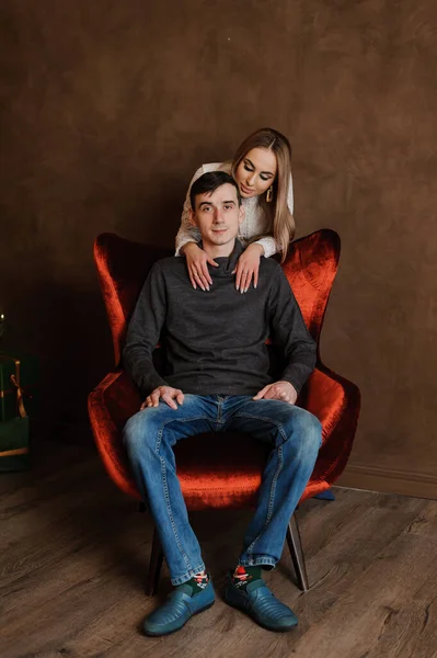 Tjejen kramar en kille som sitter på en röd stol — Stockfoto